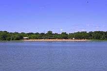 beach and trees viewed from across the lake