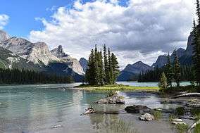 A small island with spruce trees on an alpine lake surrounded by peaks