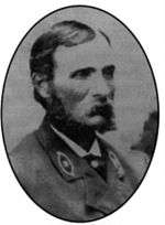 Head and shoulders of a white man with a mustache and long, bushy sideburns, wearing a suit coat with an oval emblem on each lapel.