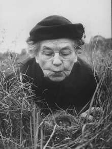 Black and white photo of elderly woman holding and examining a bird's nest