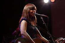 Marit Laren, a young brunette woman, playing a guitar while singing