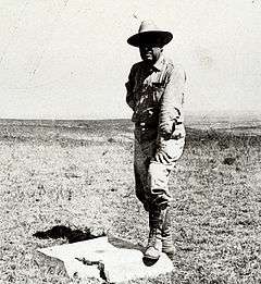 Man standing with one foot on concrete block with metal disc in center