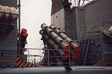 A Quartet of grey colored cylindrical canisters positioned roughly in the center of the image, with the canisters pointed at angle with the base to the lower right. A clear space can be seen in the left third of the image.