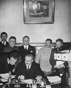 Soviet Foreign Minister Vyacheslav Molotov signs the Molotov-Ribbentrop Pact. Behind him stand German Foreign Minister Joachim von Ribbentrop and Soviet Premier Joseph Stalin.