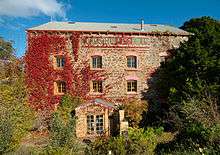 front of a three-story stone building partly covered in ivy