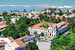 White stone church with red tile roof near the sea.