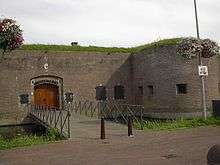 A small fortified building across a small footbridge.