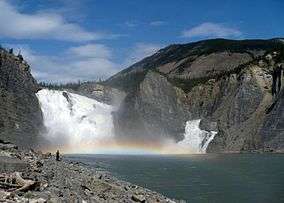 Large but relatively low waterfall through rocks.