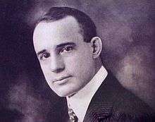 headshot of young man clad in white shirt, jacket and tie