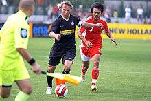 Two players vying for the ball, with a linesman nearby