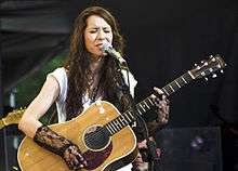 A woman playing guitar and singing into a microphone