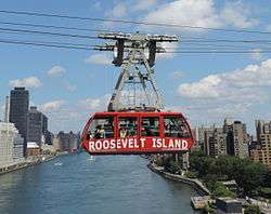 A red-colored tram going over a river