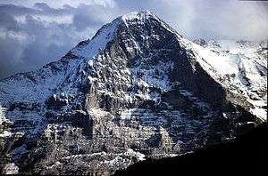 With sunlit snowfields and dark clouds in the distance