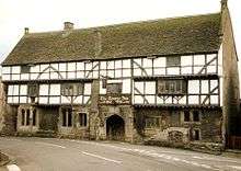 White-fronted building with black beams prominent. Over the door is a sign saying The George Inn, Wadworths.