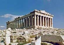 The Parthenon is a rectangular building of white marble with eight columns supporting a pediment at the front, and a long line of columns visible at the side