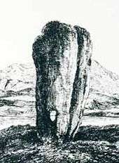  A black and white line drawing of a tall standing stone that is wider at the top than the base. It has a long vertical crack on the right hand side and there is a small hole that goes right through it near the ground. A lake and hill are in the background.