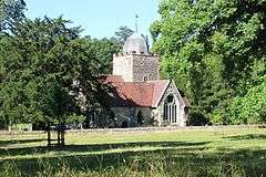 A stone church seen from the south, showing a transept with a large window, and a tower surmounted by a cupola