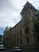 Large old stone building, with vehicles nearby for scale