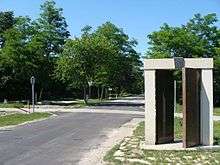 Tree-lined road with gates and a guardhouse