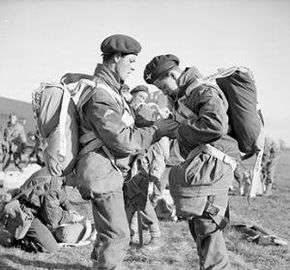 Two men in foreground checking each other's equipment