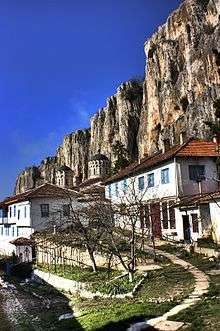 A couple of white residential buildings with cliffs in the background. Domes of a church are visible.