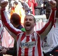 A man wearing a red and white football shirt after a game.