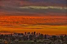 a photo of the reds and oranges of a sunset over the skyline of Phoenix, as seen from Papago park.