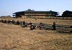 Photograph of the Petaluma Adobe, a broad, low, two-story building with wide verandas amidst open grasslands.