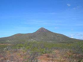 An extinct volcano with sparse greenery in the foreground