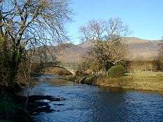 a modern, stone clad bridge over a river