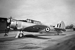 Piston-engined military monoplane parked at an airfield