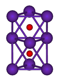 The ball-and-stick diagram shows two regular octahedra which are connected to each other by one face. All nine vertices of the structure are purple spheres representing rubidium, and at the centre of each octahedron is a small red sphere representing oxygen.