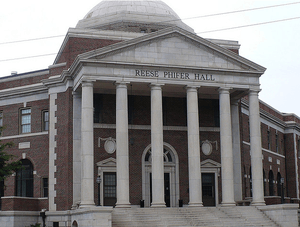 Three story red brick building with domed rotunda behind a central monumental portico