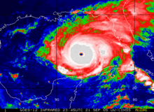 Colorized satellite image of a tropical cyclone. Bluer colors indicate areas of warmer cloud tops, indicative of marginal convective activity; redder and whiter colors indicate areas of colder cloud tops, indicating stronger convective activity.