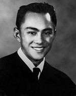 A young man in a shirt, tie and sweater. He is looking forward towards the camera and is smiling.