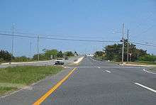 A four lane divided highway at an intersection approaching a drawbridge