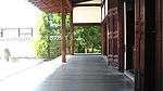 A roofed enclosing veranda of a wooden building with white walls.