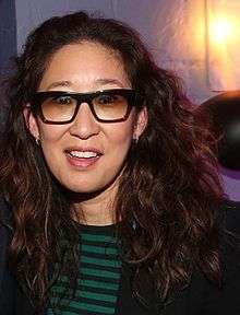 Sandra Oh smiling at the camera wearing sunglasses