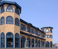 Exterior photograph of the Santa Monica Looff Hippodrome, a pink building with blue trim and large, arched glass doors and windows.