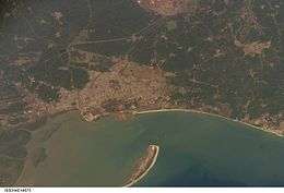 Aerial view of water, a curved shore and a sandspit