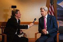 woman at left holds up microphone to John Kerry at right