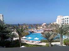 Large hotel pool, with trees in foreground and ocean in background