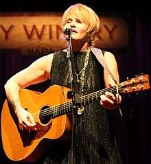 Colvin playing a guitar and singing into a microphone