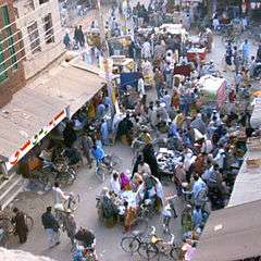 many people in colorful clothing are shopping at an open air market