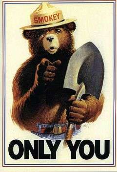 Drawing of a grizzly bear with human features. He is wearing blue jeans with a belt and a brimmed hat with the name "Smokey" on the cap, and has a shovel in his left hand. He is pointing to the viewer while the text "Only You" is seen below him.