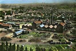 A photochrome showing a large factory with  two imposing smokestacks surrounded by bare landscape and miners houses.