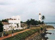 A white church and white lighthouse near the sea.