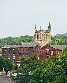 A Gothic tower projecting above rooftops, with a taller spired stair turret