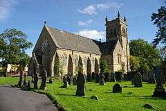 A stone church with a transept, a rose window and a pinnacled thower