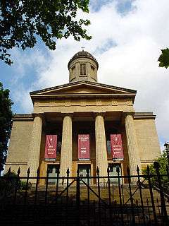 The entrance face of a church in Neoclassical style, with four columns supporting a pediment, over which is a cupola.